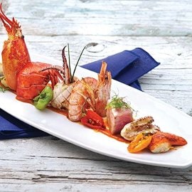 Composizione di mare alla griglia servita con caramello di peperoni gialli e misticanza Composizione di mare alla griglia servita con caramello di peperoni gialli e misticanza