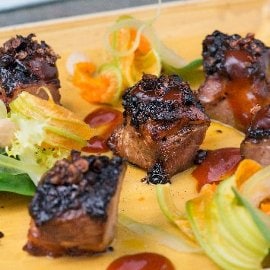 Cubi di capocollo di maiale laccato al formaggio fresco spalmabile e barbecue con insalatina di fiori di zucca, anacardi e sedano Cubi di capocollo di maiale laccato al formaggio fresco spalmabile e barbecue con insalatina di fiori di zucca, anacardi e sedano