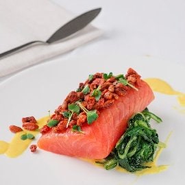Filetto di salmone in crosta di bacche di goji con crema di datterino giallo e nido di cicorielle all'aglio