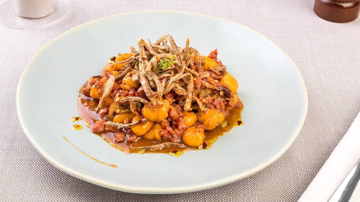Gnocchetti di patate con ragù di capretto, funghetti chiodini, fiammiferi di cardi croccanti ed olio di peperone crusco