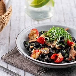 Orecchiette al nero con aringa affumicata, pomodorino gratinato e cipollotti